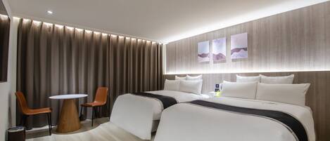 A hotel room with a large bed, two bedside tables, a small round table, and two chairs.
