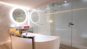 A modern bathroom with a curved white vanity, a round mirror, and a glass shower enclosure.