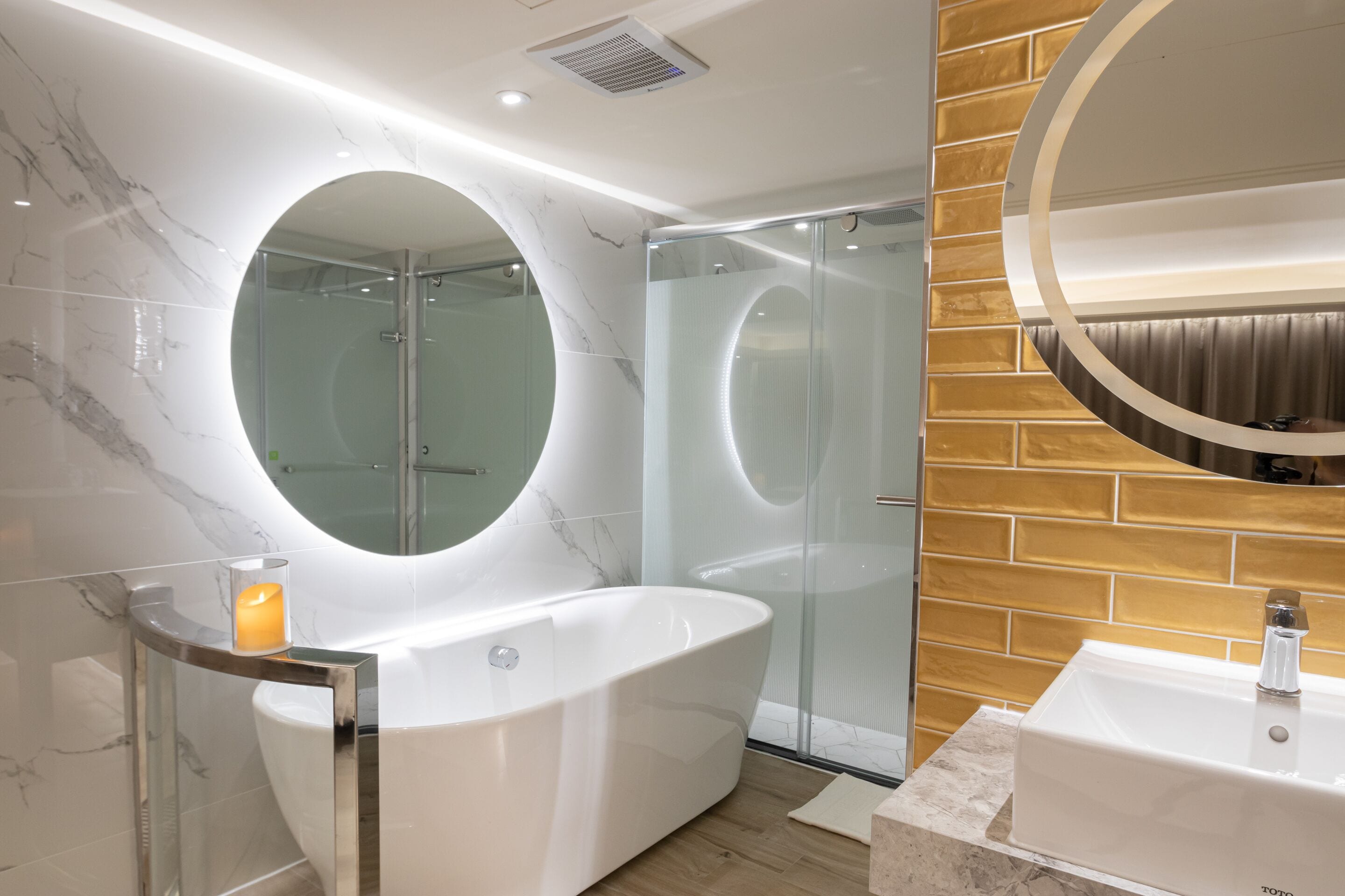 Un baño moderno con una bañera independiente, ducha con mampara de vidrio y un tocador con lavamanos.