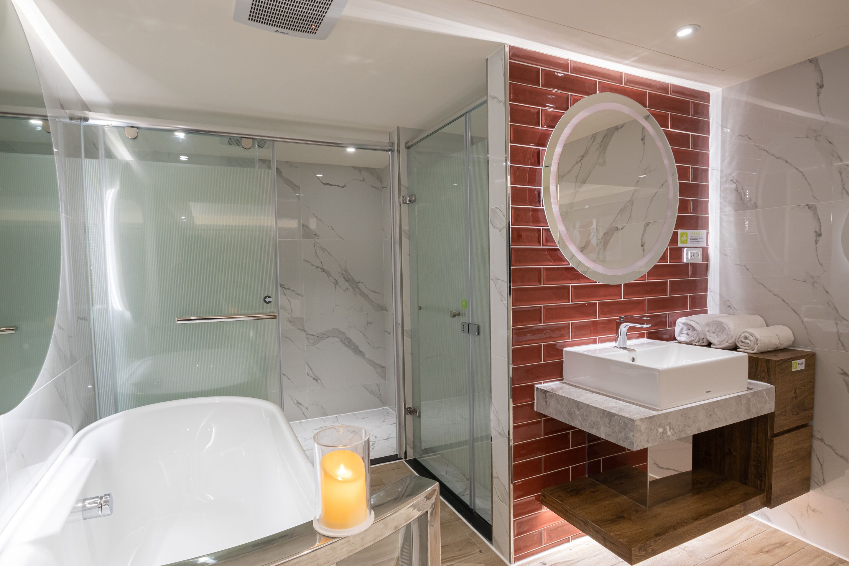 Un baño moderno con ducha envuelta en vidrio, una bañera blanca, tocador con lavabo y un espejo grande.