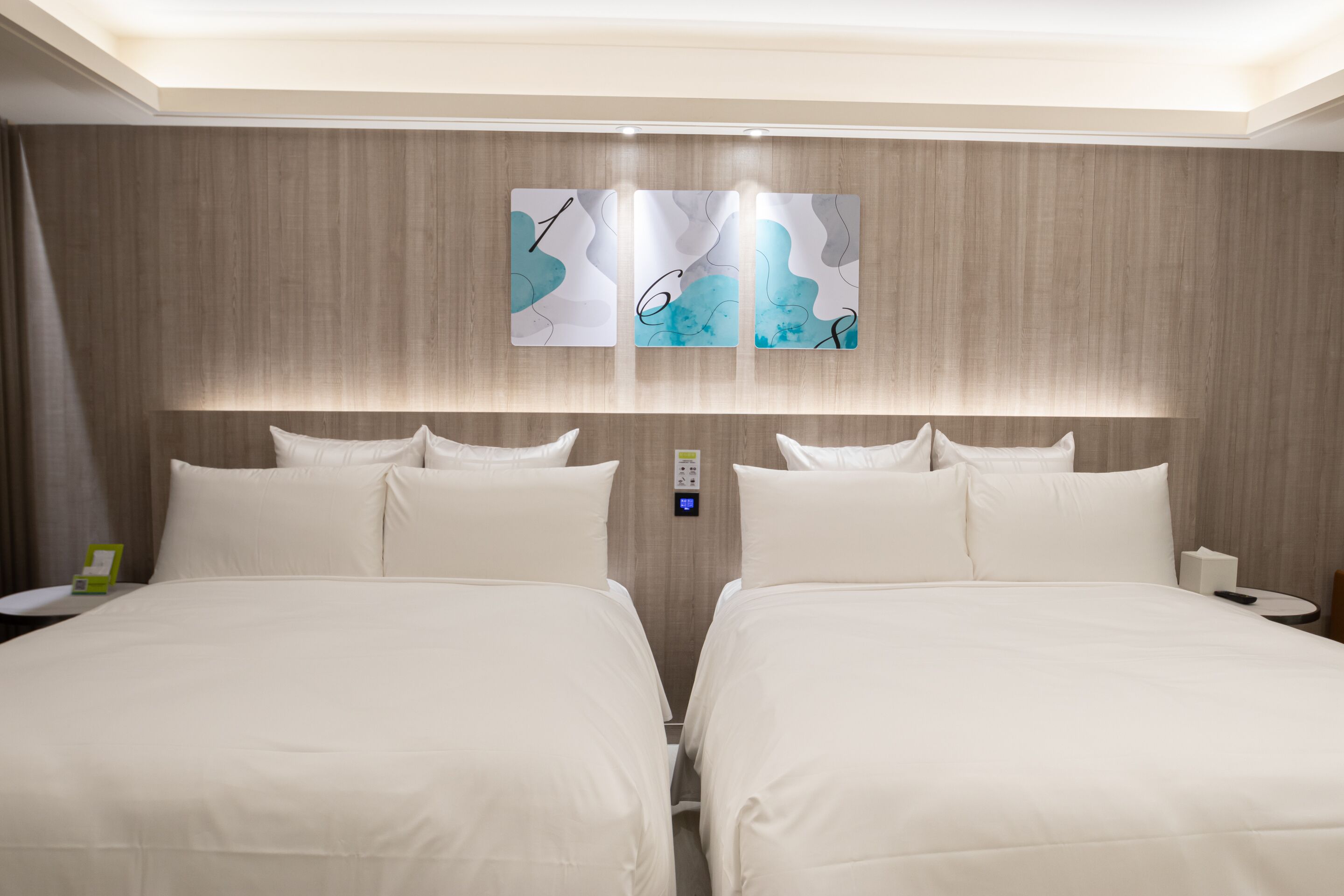 Een hotelkamer met een groot bed, een nachtkastje en een bedieningspaneel aan de muur.