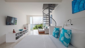 A modern bedroom with a large bed, a TV, a white console, and a staircase leading to a balcony. - Kokomo Resort Gili Gede (Gili Gede)