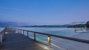 A wooden pier extending into calm waters with boats docked nearby. - Kokomo Resort Gili Gede (Gili Gede)