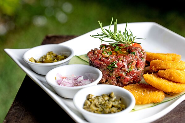 A plate of steak tartare with garnishes and sides.