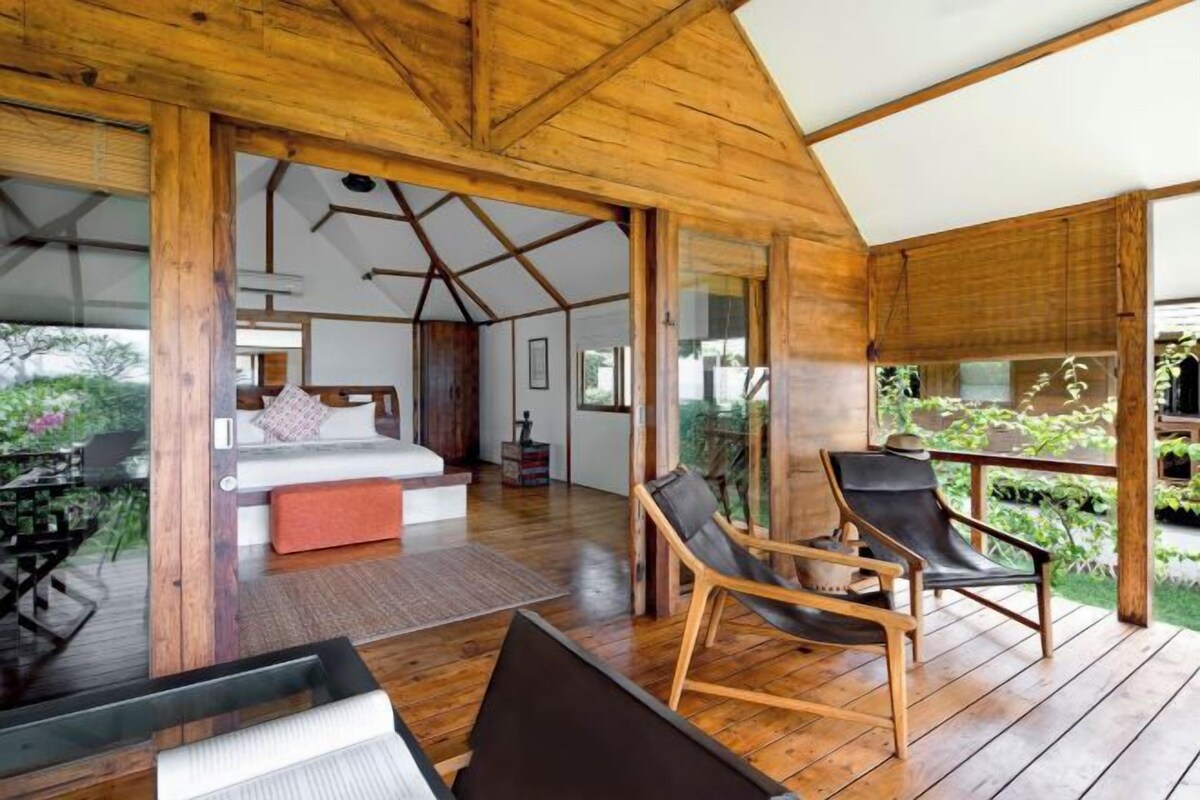 Una habitación amplia con techo de madera, una cama, un escritorio y una silla.