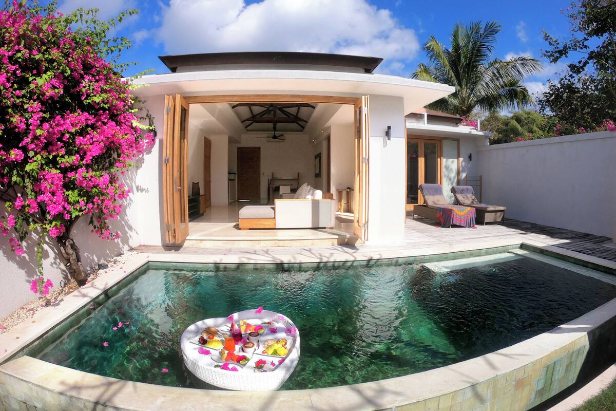 A modern house with a swimming pool, a dining area, and a lounge with outdoor seating.
