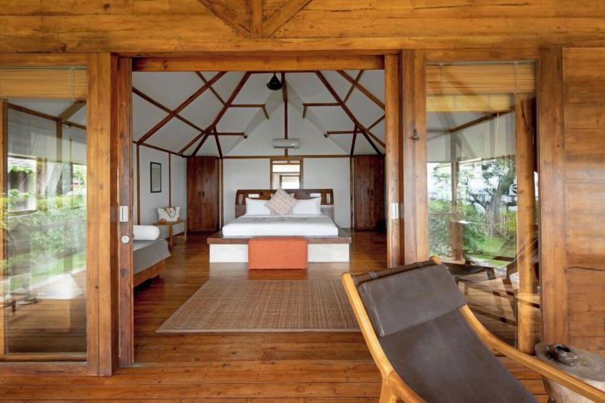 Una cabaña de madera con una cama grande, zona de estar y vistas al exterior.