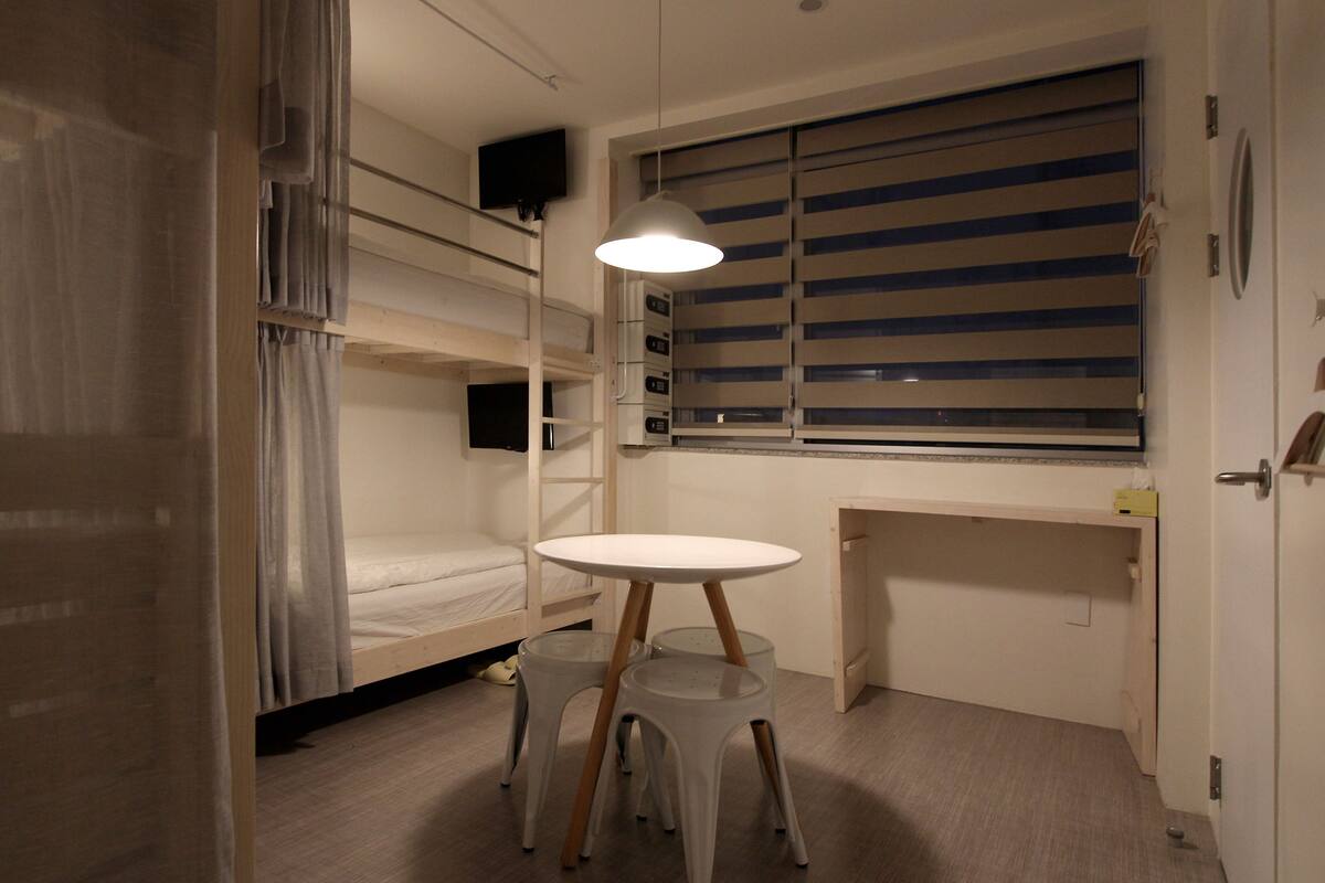 Ein kleines Zimmer mit Etagenbetten, einem kleinen Schreibtisch und einem Tisch.