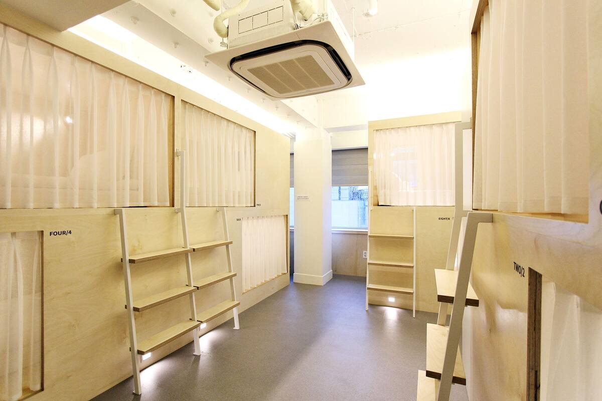 Ein Zimmer mit Holzbögen, auf denen 'FOUR/4' und 'TWO/2' stehen, einer Decken-Klimaanlage und einem Fenster mit Jalousien.