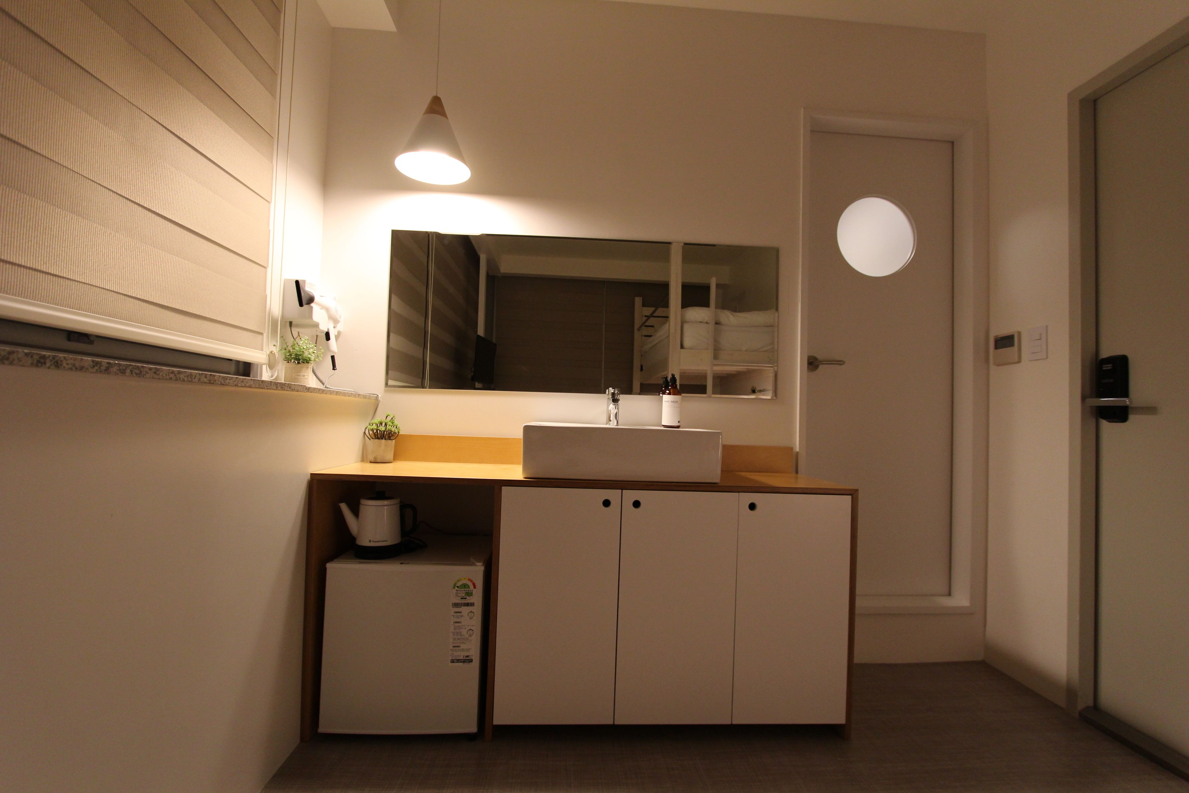Un baño pequeño con lavamanos, espejo y un mueble bajo.