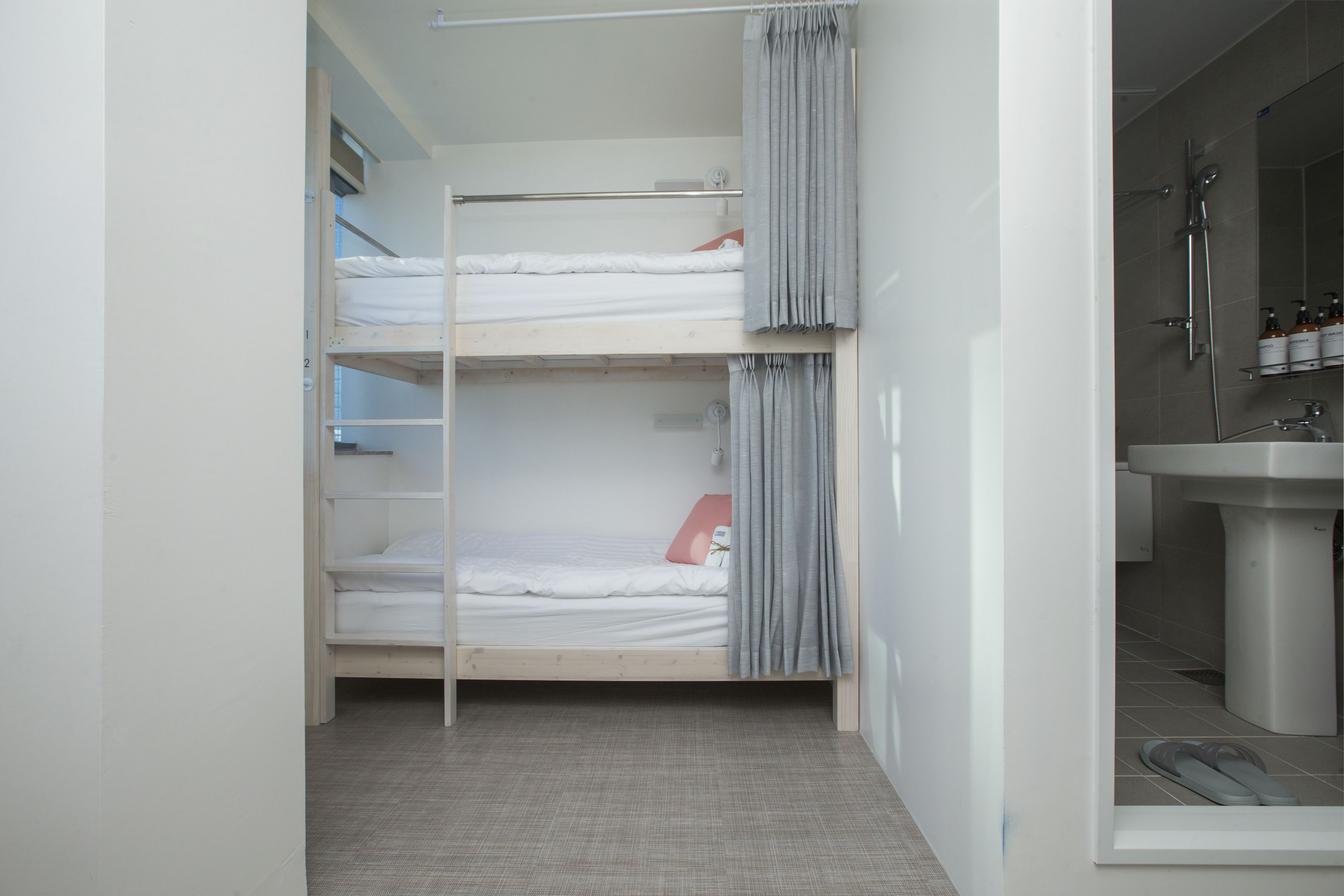 A bunk bed room with a bathroom containing a sink and shower.