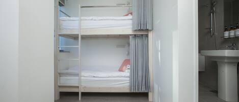 A bunk bed room with a bathroom containing a sink and shower.