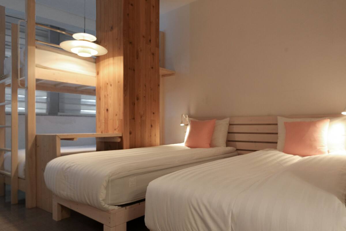 Ein Schlafzimmer mit zwei Betten, einer Holzleiter und einer weißen Wand.