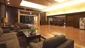 A spacious lobby with a reception desk, seating area, and a staircase leading to an upper floor.