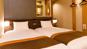 A hotel room with a large bed, a mirror, and two wall-mounted light fixtures.
