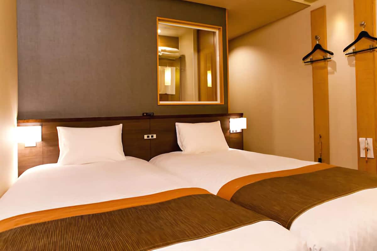 Une chambre d’hôtel avec un grand lit, un miroir et deux appliques murales.