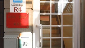 Eine Tür mit einem Fenster, ein Schild mit den Buchstaben "bnb" und "R4", und ein rotes Schild mit "K01 K02 K03".