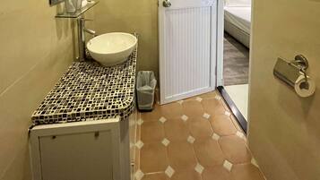 A compact bathroom with a white sink, a mirror, and a small trash bin.