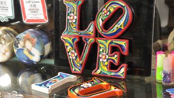 A display of colorful, floral-patterned letters spelling "LOVE" on a reflective surface, surrounded by various decorative items.