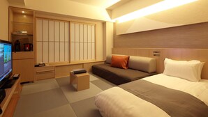 A hotel room with a bed, a sofa, a TV, a desk, and a sliding door. - Cocochee Hotel Numazu (Numazu)