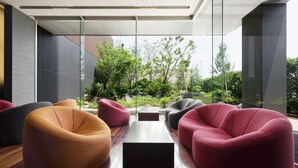 A modern outdoor seating area with contemporary furniture and a view of greenery and buildings. - Cocochee Hotel Numazu (Numazu)