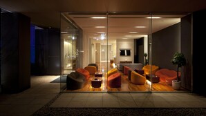 A modern hotel lobby with glass walls, wooden flooring, and contemporary seating areas. - Cocochee Hotel Numazu (Numazu)