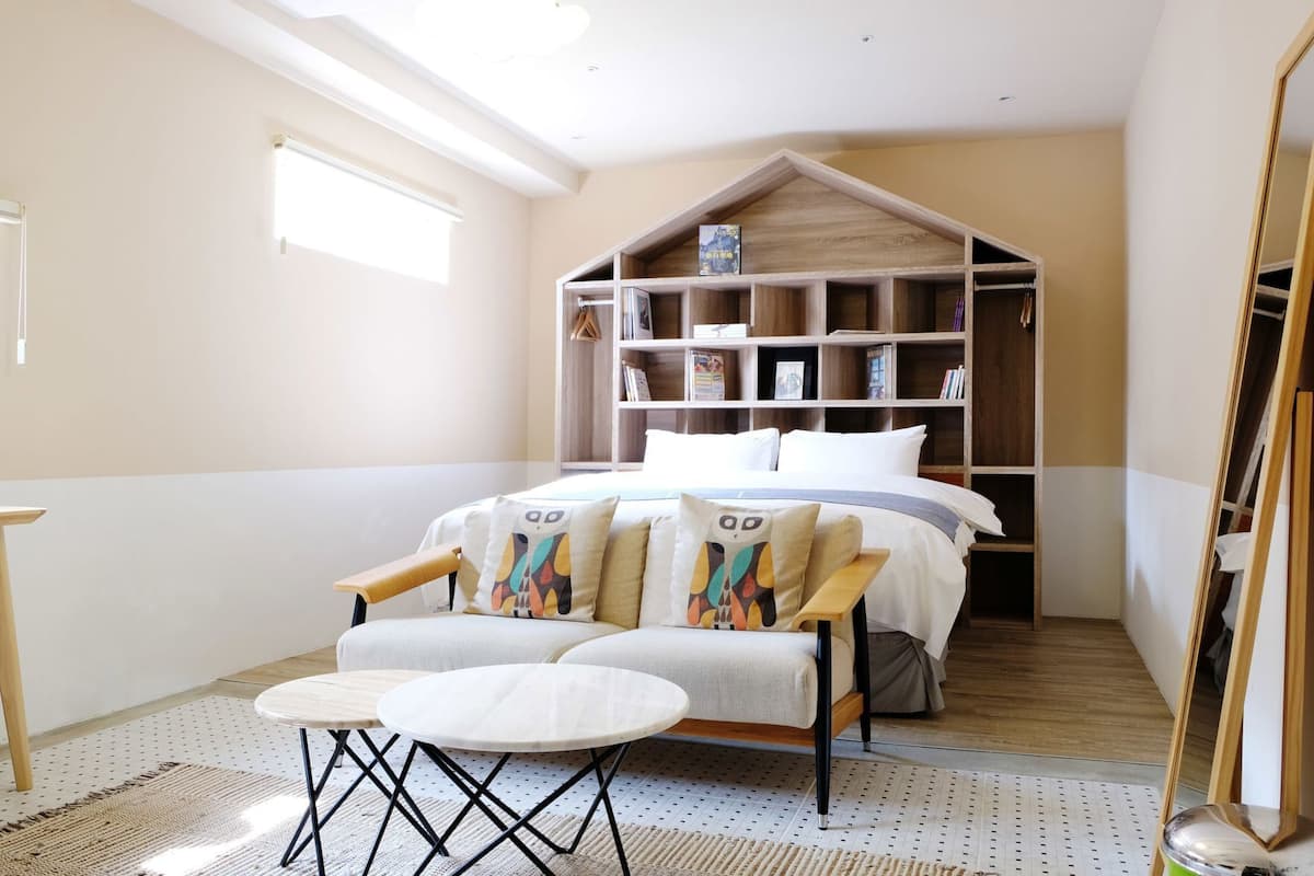 A bedroom with a bed, a built-in bookshelf, a small table, and a chair.