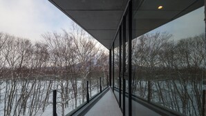 A corridor with large windows overlooking a snowy landscape and a body of water. - Kozue (Kutchan)