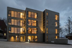 Un immeuble moderne à plusieurs étages, doté de grandes fenêtres et d’un hall d’entrée bien éclairé.