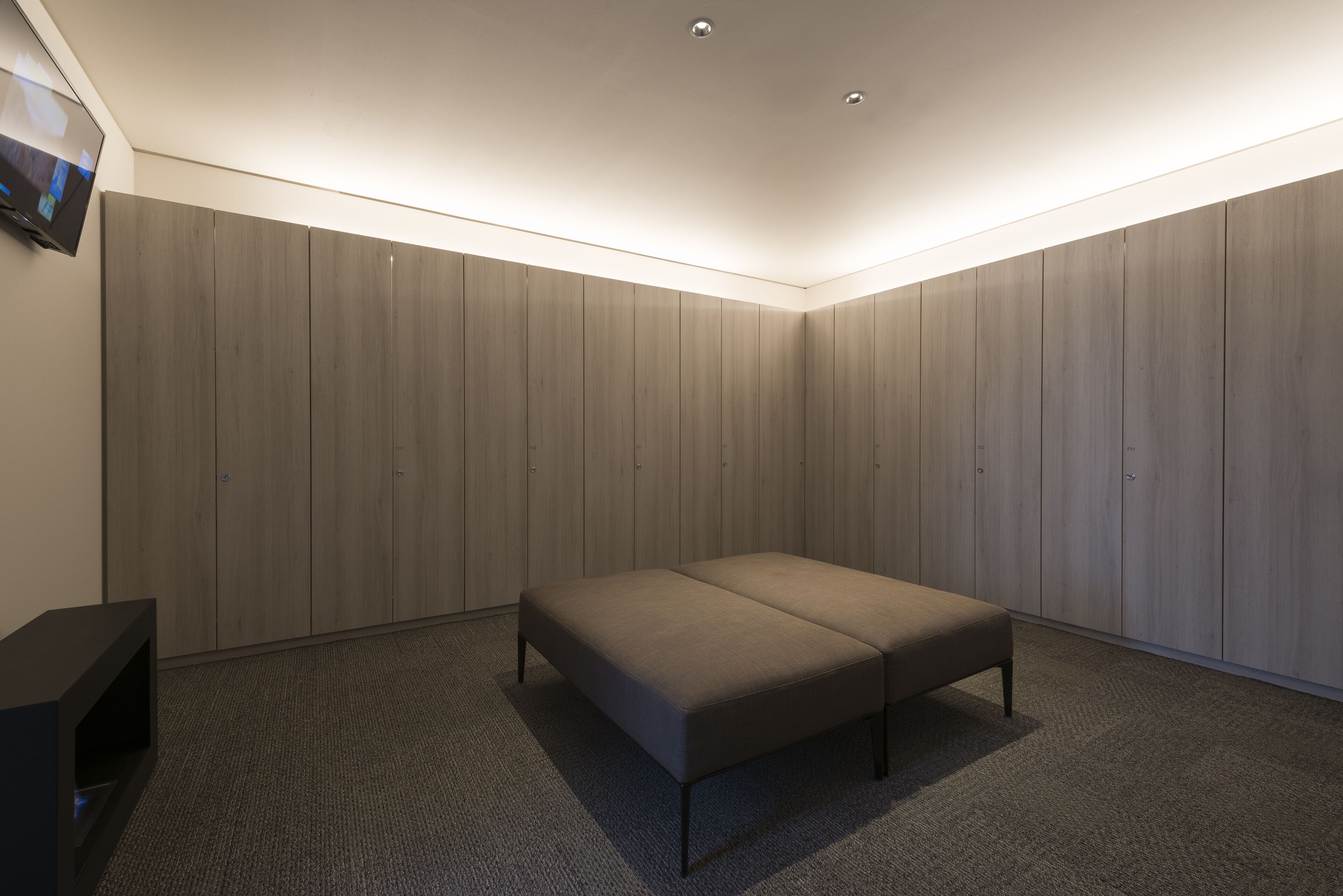Un dormitorio con cama, televisor de pantalla plana y paneles de madera.