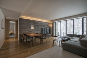 Un salon moderne avec un coin repas, une grande fenêtre et un mur en pierre.