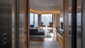 An interior view of a modern elevator leading to a living area with a sofa, chairs, and a large window. - Kozue (Kutchan)