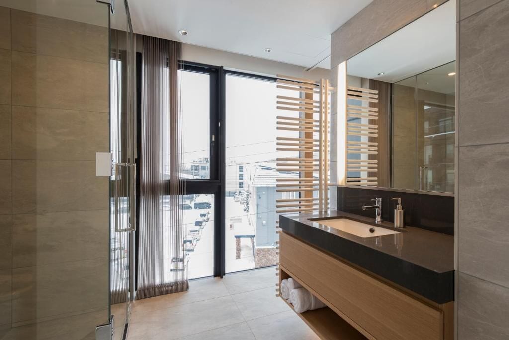 Un bagno moderno con uno specchio grande, un lavandino e una zona doccia.