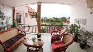 A balcony with wicker furniture, potted plants, and a view of a cityscape. - RS guesthouse (Phnom Penh)