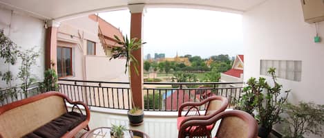 Un balcon agrémenté de meubles en osier, de plantes en pot et offrant une vue sur le paysage urbain.