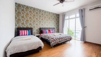 A bedroom with two beds, a ceiling fan, and a large window with curtains.