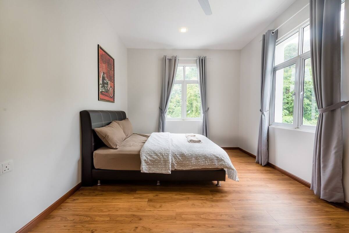 A bedroom with a bed, a window, and a painting on the wall.