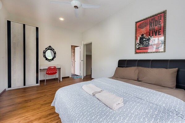 A bedroom with a bed, a desk, a chair, a mirror, and a poster on the wall. - New Corner Shamrock Beach Villas Seaview (George Town)