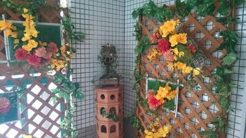 Una esquina de habitación con un muro de diseño en cuadrícula, una columna de terracota y una celosía de madera adornada con flores.