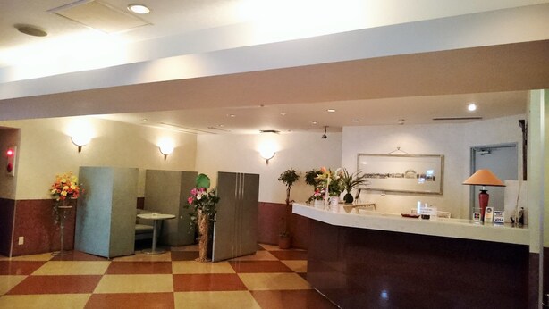 A hotel lobby with a reception desk, a check-in counter, and a restroom area.