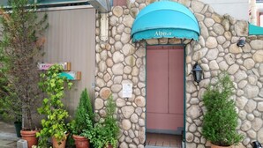 A stone building with a blue awning labeled "Alpina" and a sign that reads "STAY".