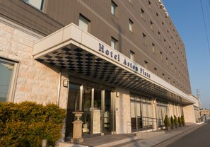 A hotel with a checkered awning, stone facade, and multiple windows. - Hotel Aston Plaza Himeji (Himeji)