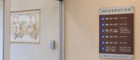 A hotel information sign listing room numbers and their corresponding features, such as guest rooms and a coin-operated laundry machine.