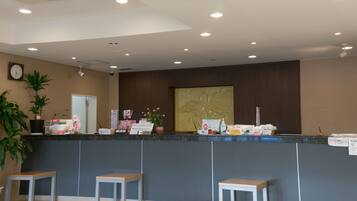 A reception area with a counter, seating, a clock, and a plant.