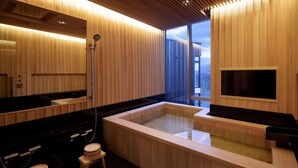 A modern spa with a large wooden bathtub, a separate shower area, and a small seating area with a stool. - Terrazze Niseko (Kutchan)