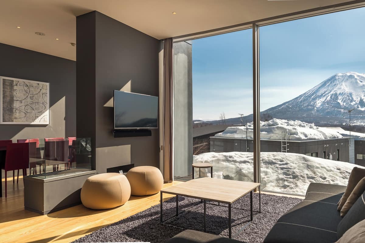 A modern living room with a large window offering a view of a snow-covered mountain.