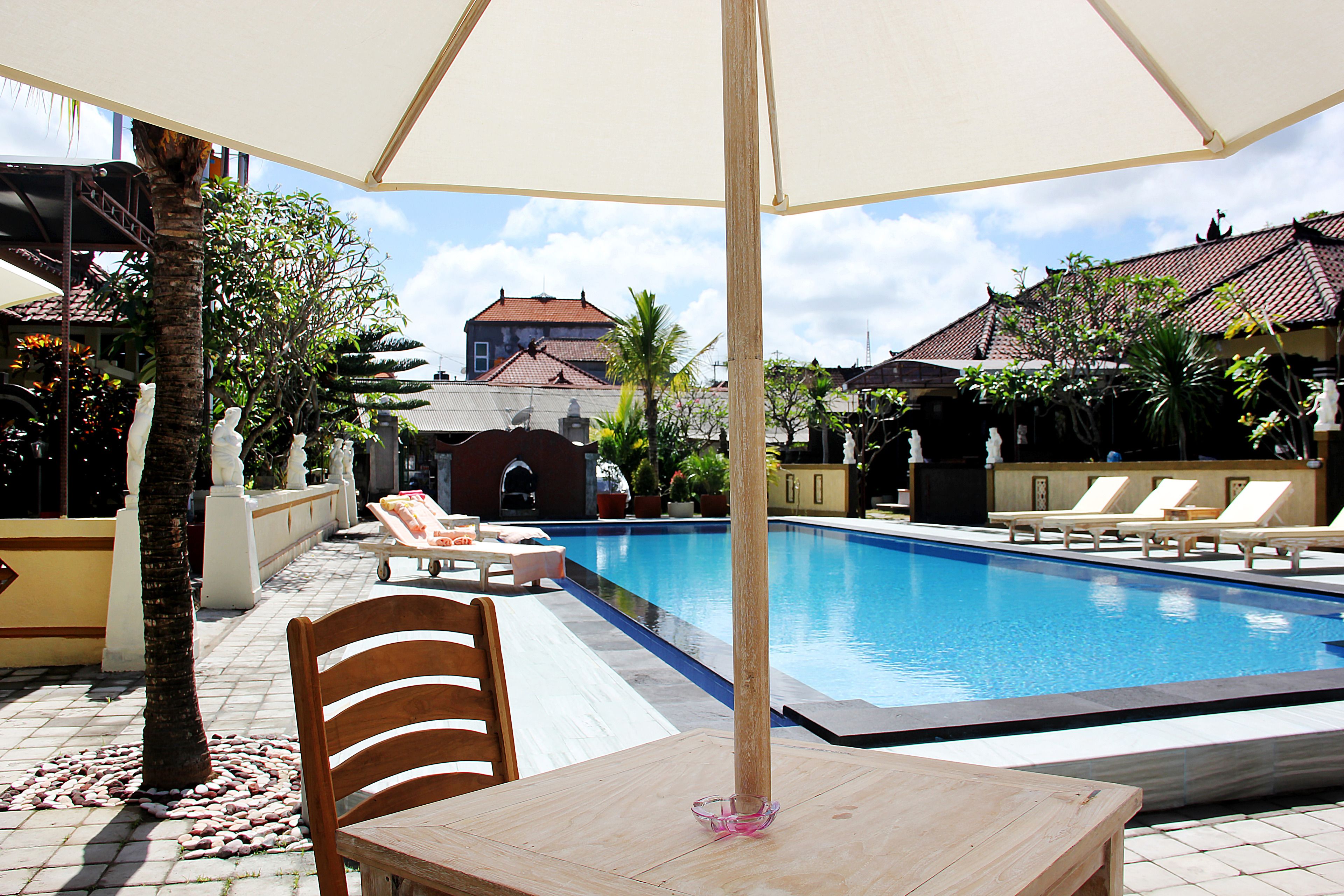 A pool area with lounge chairs, a table, and a large umbrella.