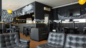 A modern bar area with a mountain-themed mural, leather seating, and a bar counter with a variety of bottles. - Hakuba Echo Hotel (Hakuba)