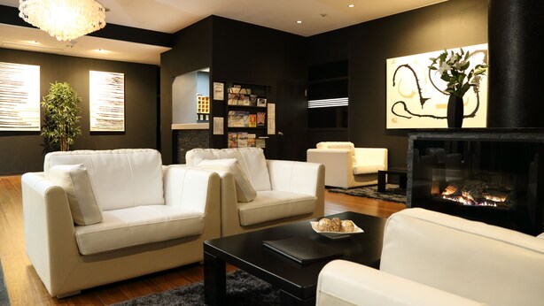 A modern living room with a fireplace, white sofas, a coffee table, and a bookshelf. - Hakuba Echo Hotel (Hakuba)