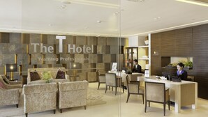 A hotel reception area with a modern design, featuring a reception desk, seating area with sofas, and a large wall with the hotel's name. - The T Hotel (Hong Kong)